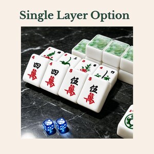 May include: A set of white Mahjong tiles with red and black Chinese characters and green floral patterns, accompanied by two translucent blue dice. The text 'Single Layer Option' is displayed above the tiles in a dark green font.