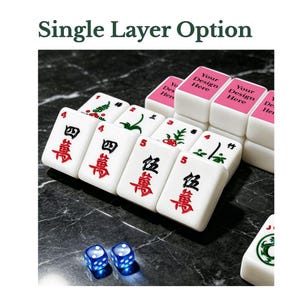 Puede incluir: Un juego de fichas de mahjong blancas con varios grabados de caracteres y palos en rojo, verde y negro, junto a dos dados azules transl&uacute;cidos. Varias fichas tienen una superficie superior rosa con el texto Your Design Here.