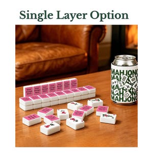 Puede incluir: Un juego de fichas de mahjong blancas con etiquetas de texto personalizadas en rosa que dicen Your Design Here y motivos florales rojos y verdes, junto a un enfriador de latas blanco con texto verde y gr&aacute;ficos de mahjong. Texto: Single Layer Option.