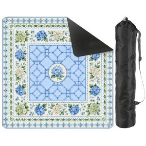 May include: A square outdoor blanket featuring a light blue lattice pattern with a central blue hydrangea motif, surrounded by a border of blue and white hydrangea clusters and green leaves, with a black underside and a black carrying bag.