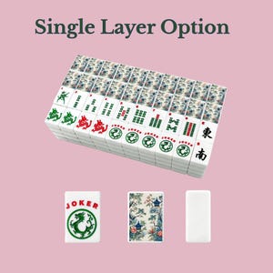 Op de afbeelding: Een set rechthoekige mahjongtegels gerangschikt in een enkele laag. De tegels zijn voorzien van groene en rode draaksymbolen, jokertekst en Chinese karakters. Sommige tegels tonen een gedetailleerd bloemen- en pagodepatroon op de achterzijde.