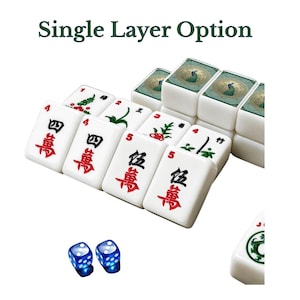 Puede incluir: Un juego de fichas de mahjong blancas con caracteres chinos en rojo y negro y motivos de bamb&uacute; verdes, junto a dos dados azules transl&uacute;cidos. El texto 'Single Layer Option' aparece sobre las fichas, que incluyen ilustraciones de pavos reales.