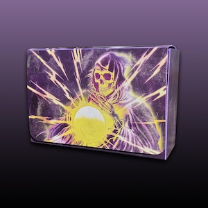 May include: A purple box featuring a glowing yellow illustration of a skeleton in a hooded cloak holding a bright orb. The artwork has a vintage, distressed look with radiating light beams.