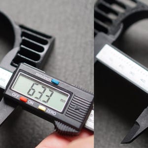 Puede incluir: Primer plano de un objeto negro que se mide con un calibrador digital. El calibrador muestra medidas de 63,3 mm y 52,0 mm. El objeto tiene un dise&ntilde;o circular con una serie de aberturas rectangulares.