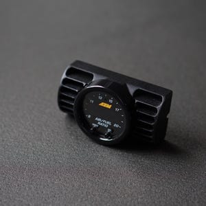 Puede incluir: Medidor de relaci&oacute;n aire/combustible negro con pantalla digital. El medidor tiene una carcasa negra con ranuras verticales en los lados. La esfera muestra n&uacute;meros y el texto "AIR/FUEL RATIO".