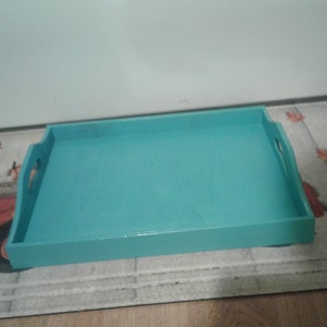 May include: A teal blue wooden serving tray with two handles. The tray is rectangular and has a smooth surface.
