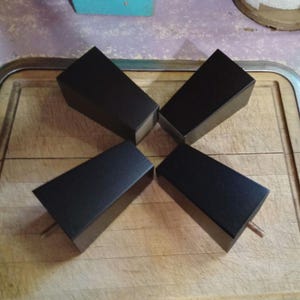 May include: Four dark brown wooden furniture legs on a light brown wooden surface.