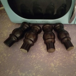 May include: Four dark brown wooden furniture legs with a rounded top and a slightly flared base.