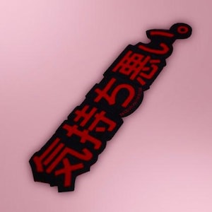May include: A rectangular sticker with a black background and bold red Japanese characters that read 気持ち悪い. The sticker features a die-cut edge that follows the contour of the text, creating a sharp and distinct visual appearance for the design.