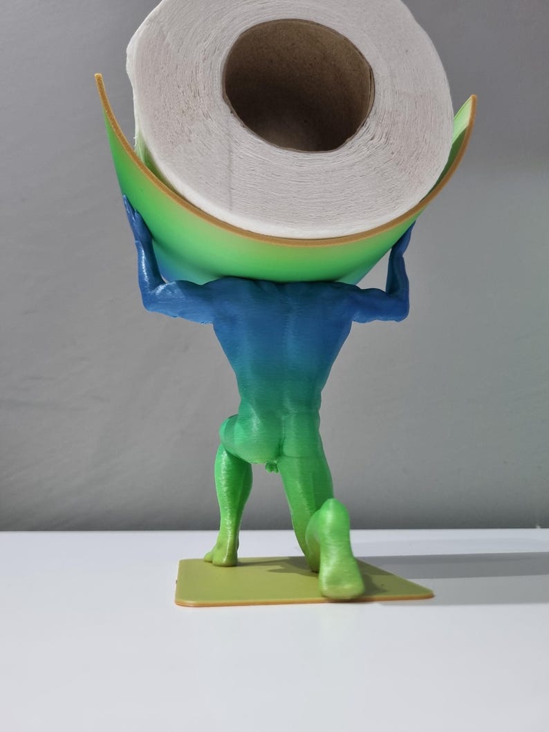 May include: A green, blue, and yellow 3D printed figurine of a person holding a roll of toilet paper. The figurine is kneeling on a small, yellow base.