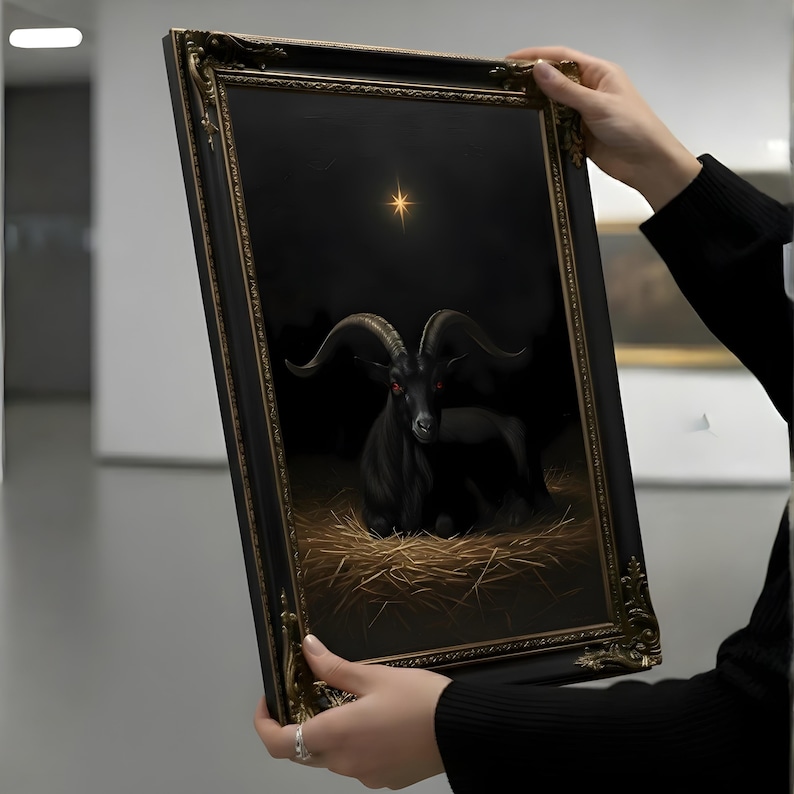 May include: A framed artwork depicting a black goat with red eyes, resting on straw against a dark backdrop. A golden star shines above the goat. The ornate frame has a gold and black finish.