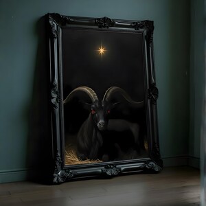 May include: A framed artwork depicting a black goat with red eyes, set against a dark backdrop with a shining star. The goat is resting on straw. The ornate black frame enhances the gothic style.