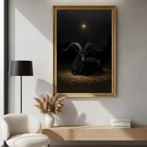 May include: A framed artwork shows a black goat with large horns and red eyes, resting on straw. The goat is set against a dark background with a golden star. The frame is gold, and the artwork is displayed in a well-lit room.