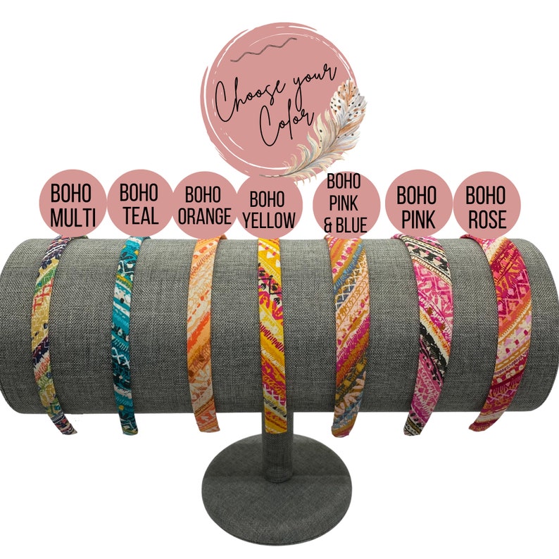 May include: A display of eight colorful headbands with different patterns. The headbands are arranged on a gray headband stand. The headbands are labeled with the colors: multi, teal, orange, yellow, pink & blue, pink, and rose.