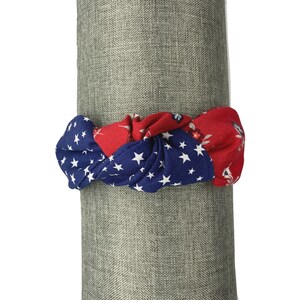 May include: A red, white, and blue knotted headband with a star pattern. The headband is made of fabric and is perfect for adding a touch of patriotism to any outfit.