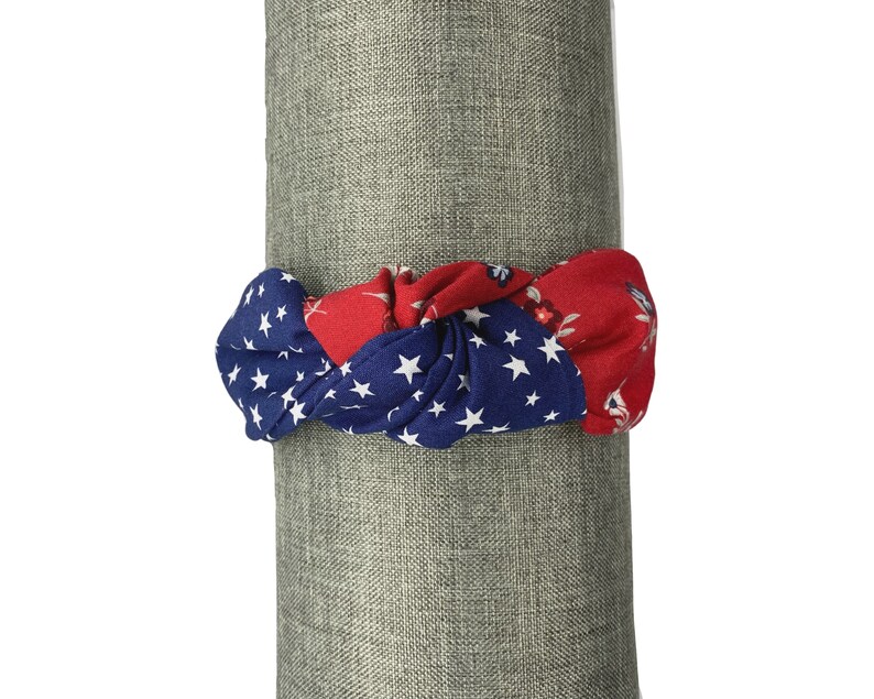 May include: A red, white, and blue knotted headband with a star pattern. The headband is made of fabric and is perfect for adding a touch of patriotism to any outfit.