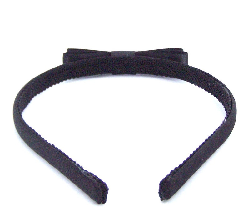 May include: A black headband with a black velvet bow. The headband is made of a soft, stretchy material.