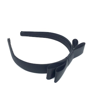 May include: A black satin headband with a large bow. The headband is made of a soft, stretchy material and is perfect for adding a touch of elegance to any outfit.