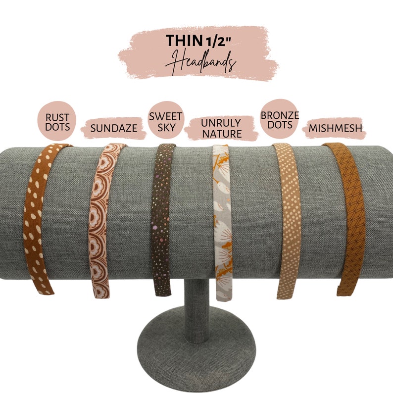 Op de afbeelding: Zes verschillende gepatroneerde dunne 1/2 inch hoofdbanden die op een hoofdbandenstandaard worden getoond. De hoofdbanden zijn gelabeld met "Rust Dots", "Sundazes", "Sweet Sky", "Unruly Nature", "Bronze Dots" en "Mishmesh".