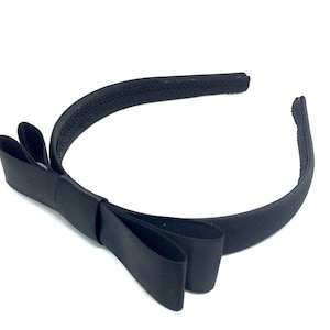 May include: A black satin headband with a large bow. The headband is made of a soft, stretchy material and is perfect for adding a touch of elegance to any outfit.