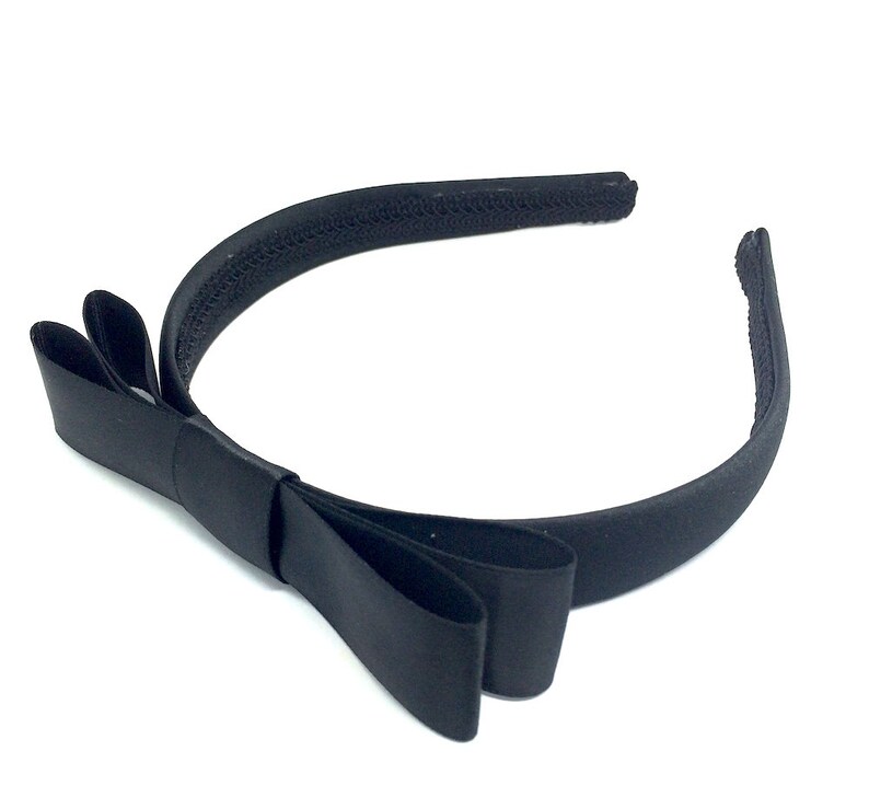 May include: A black satin headband with a large bow. The headband is made of a soft, stretchy material and is perfect for adding a touch of elegance to any outfit.