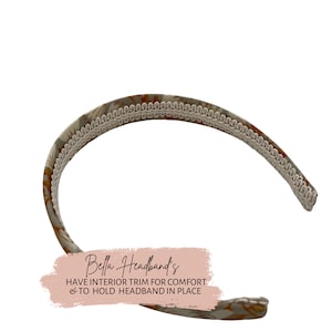 Op de afbeelding: Een beige hoofdband met een bloemenprint en witte bies. De hoofdband heeft een tekstoverlay die "Bella Headbands" en "Have interior trim for comfort & to hold headband in place" luidt.