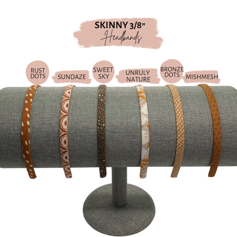 Op de afbeelding: Zes verschillende gepatroneerde haarbanden die op een grijze standaard worden getoond. De haarbanden zijn 3/8 inch breed en hebben patronen zoals roest stippen, Sundaze, Sweet Sky, Unruly Nature, bronzen stippen en mishmesh.