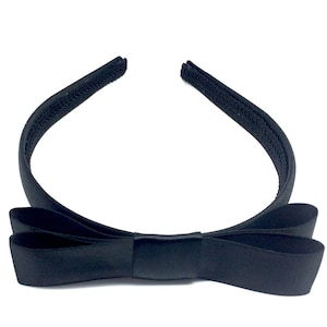 May include: A black satin headband with a large bow. The headband is made of a soft, stretchy material and is perfect for adding a touch of elegance to any outfit.
