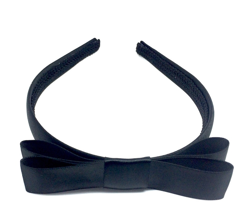 May include: A black satin headband with a large bow. The headband is made of a soft, stretchy material and is perfect for adding a touch of elegance to any outfit.