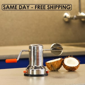 May include: A stainless steel coconut grater with an orange handle and a serrated blade. Two halves of a coconut are next to the grater. The text "SAME DAY - FREE SHIPPING" is at the top of the image.