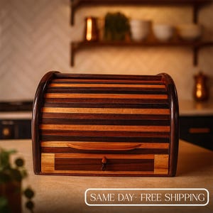Puede incluir: Una panera de madera con tapa enrollable y un cajón. La panera está hecha de varios tonos de madera, incluyendo marrón oscuro, marrón medio y marrón claro. El cajón tiene un pequeño tirador de madera y un pomo decorativo de madera. El texto "SAME DAY - FREE SHIPPING" está en la parte inferior.