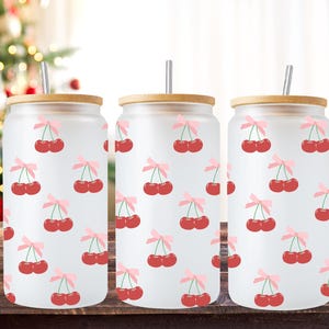 May include: Three frosted glass tumblers with bamboo lids and stainless steel straws. Each tumbler features a repeating pattern of red cherries with pink bows on a white background.