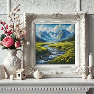 May include: A framed landscape painting depicts a mountain scene with a river flowing through a green valley. The white ornate frame sits on a white mantel, next to a vase of flowers and a candle.