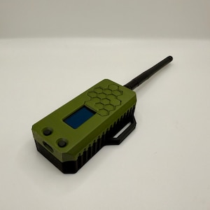 May include: A green and black handheld radio transmitter with a honeycomb pattern on the top and a black antenna. The radio has a small screen and two buttons.