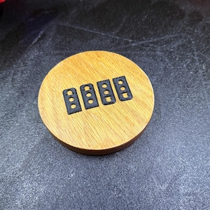 May include: Five black plastic pieces with small holes in them, arranged on a wooden surface.