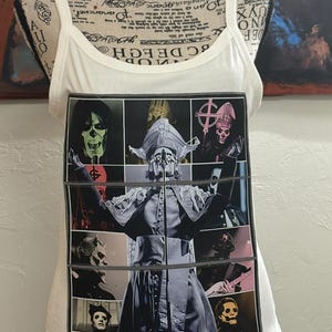 May include: White ribbed vest top with a large graphic print. The graphic features a collage of images of a band member in various poses and costumes. The images are framed in a black border.
