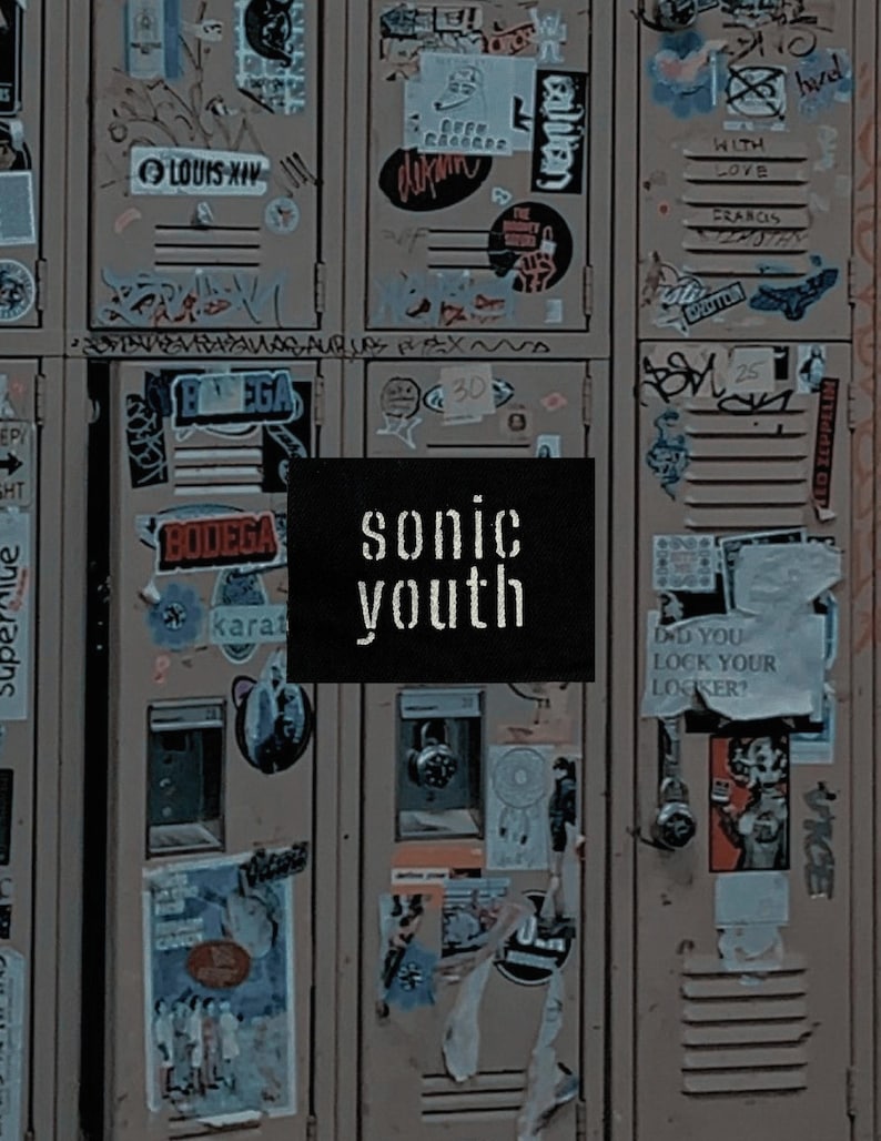 May include: A close-up of a series of lockers covered in stickers and graffiti. A black square with the words "sonic youth" in white lettering is centered in the image. The lockers are a muted brown color.