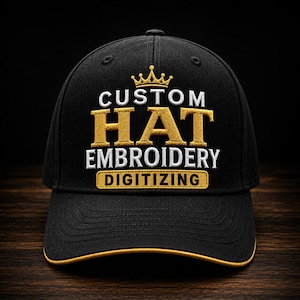 May include: A black baseball cap featuring gold and white embroidery on the front. The design includes a gold crown icon above the text CUSTOM HAT EMBROIDERY, with the word DIGITIZING inside a gold rectangular border. The brim has a gold trim.