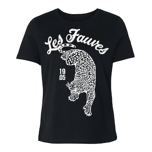May include: A black short-sleeved t-shirt featuring a white graphic of a leopard in a pouncing position. Above the leopard, the text Les Fauves is printed in a white script font. To the left of the leopard, the numbers 19 and 05 are stacked vertically.