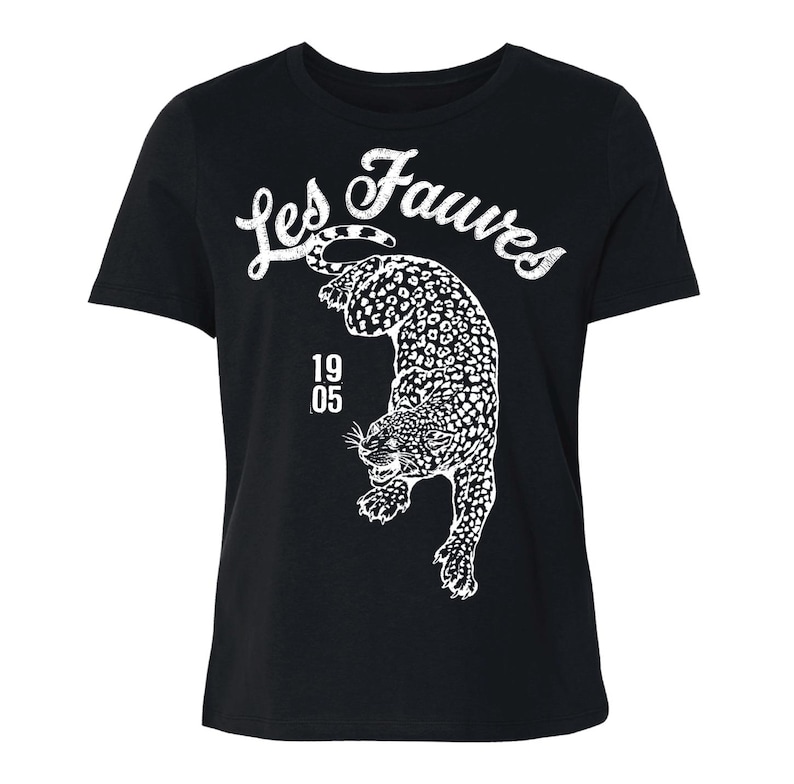May include: A black short-sleeved t-shirt featuring a white graphic of a leopard in a pouncing position. Above the leopard, the text Les Fauves is printed in a white script font. To the left of the leopard, the numbers 19 and 05 are stacked vertically.