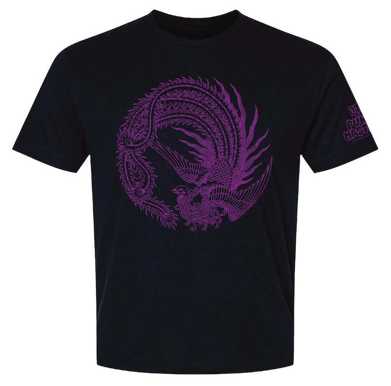 K&ouml;nnte beinhalten: Ein schwarzes Kurzarm-T-Shirt mit einer gro&szlig;en, kreisf&ouml;rmigen violetten Grafik eines Ph&ouml;nix mit detaillierten Federn. Auf dem &Auml;rmel befindet sich der violette Schriftzug "THE PUNK MASTERS" in einer stilisierten, abgerundeten Schrift auf dem Stoff.