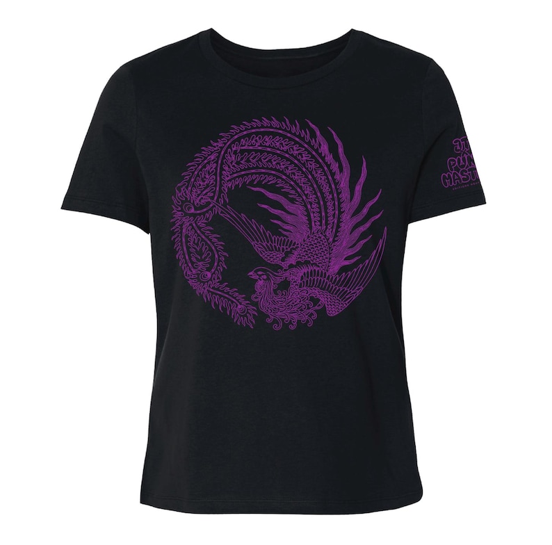 K&ouml;nnte beinhalten: Ein schwarzes Kurzarm-T-Shirt mit einer kreisf&ouml;rmigen violetten Grafik eines Ph&ouml;nix mit detaillierter Federzeichnung. Auf dem rechten &Auml;rmel befindet sich der violette Schriftzug "THE PUNK HASTA". Das T-Shirt hat einen Rundhalsausschnitt.