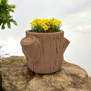 May include: A brown, tree-stump-shaped planter filled with vibrant yellow flowers. The planter has a textured surface and three protruding branch stubs. The flowers are a bright contrast to the planter's earthy tones, creating a natural aesthetic.
