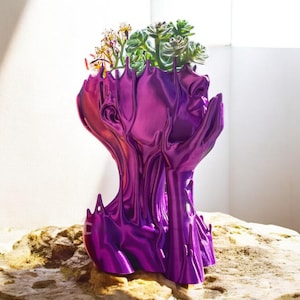 May include: A purple, abstract, human-shaped planter with a face and hands, holding succulents and flowers.