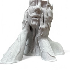 May include: A white, abstract sculpture of a person's head with hands covering the face. The sculpture is made of a smooth, textured material and has a flowing, organic shape.