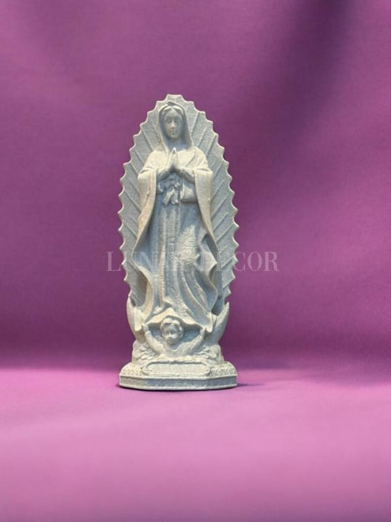 May include: A light grey statue of the Virgin Mary, with hands clasped in prayer. The statue is set against a purple background. The text "LUN DECOR" is visible on the image.