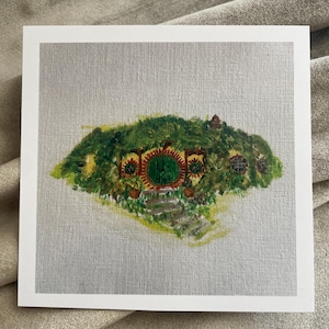 May include: A painting of a hobbit hole, a round green door with a red and yellow frame, surrounded by green foliage and a stone path leading to the door.