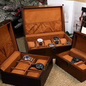 Może przedstawiać: Kilka otwartych drewnianych pudełek na zegarki, każde z wieloma przegródkami i wyłożone beżową tkaniną. Pudełka prezentują różne zegarki na rękę ze skórzanymi i metalowymi paskami. Pudełka są ułożone na teksturowanej powierzchni.