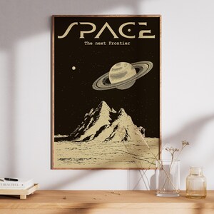 Puede incluir: Un póster en blanco y negro con el texto "SPACE The next Frontier" en una fuente retro. El póster presenta una imagen estilizada de un planeta con anillos, montañas y un cielo estrellado.