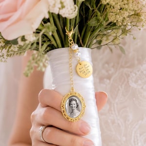 May include: A gold-toned metal photo charm featuring an oval frame with an ornate filigree border, a small round disc engraved with the text "Now Its Your Turn 08 24 2026", and two white faux pearls, all attached to a delicate chain with a lobster clasp.